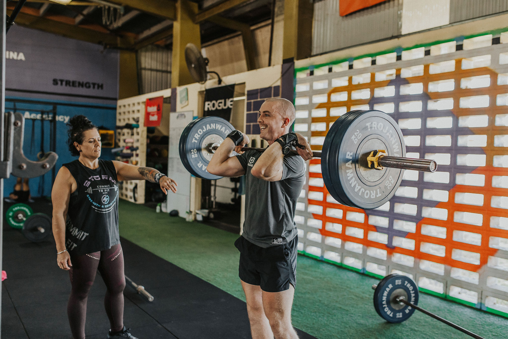 Members lined up lifting barbells during a strength class